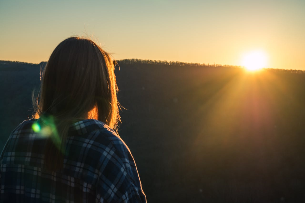 A woman views a beautiful sunset over hills in Fayetteville, Arkansas, showcasing natures serene beauty.